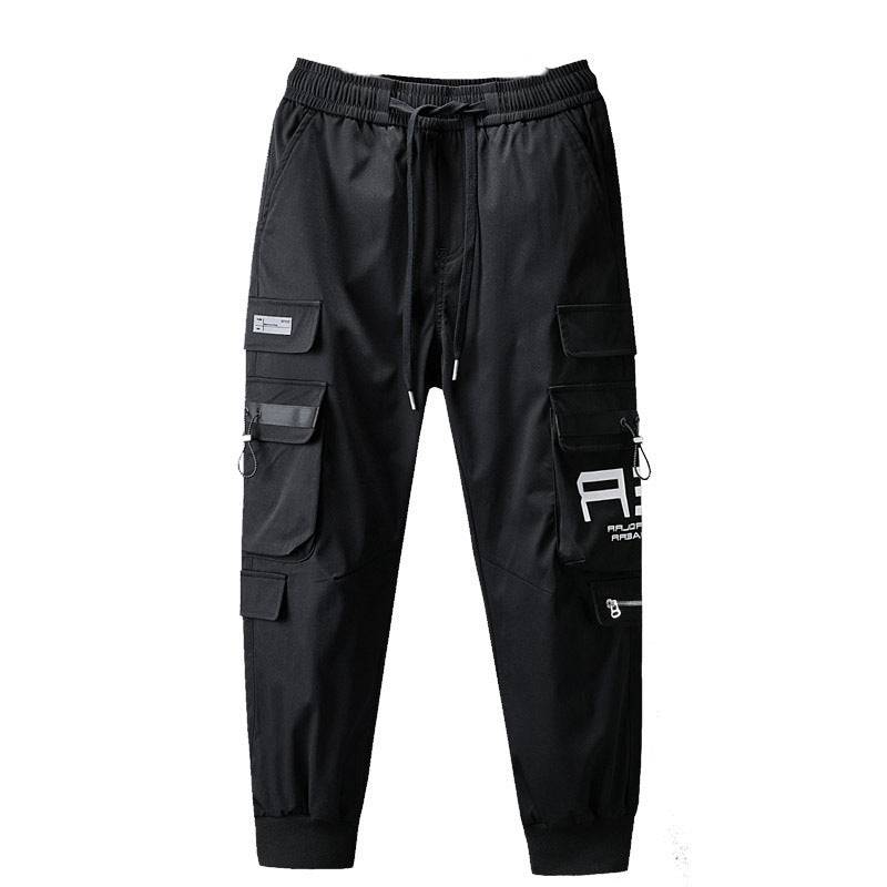 Black men's casual workwear pants with drawstring waist, zippered and flap pockets, and bold white graphic print on the leg.