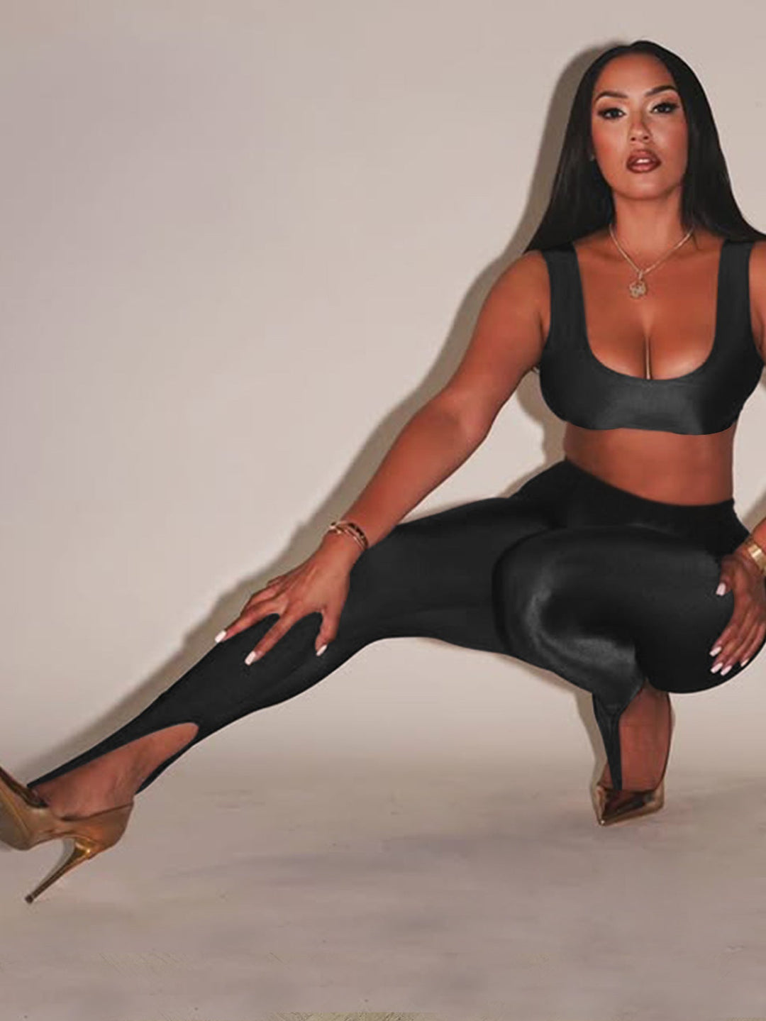 Front Step Shiny Leggings - Slim Fit Nylon Trousers in black, high-gloss finish with stirrup hem, styled with crop top and gold heels.